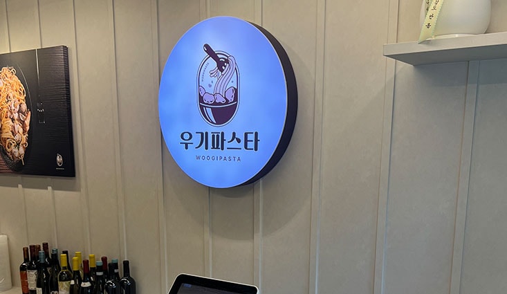 우기파스타 원형 로고 사인이 걸린 매장 벽면